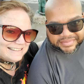 An image of Invictuz and BebeBlueEyes on the day of Bebe's collaring. She is wearing her Leather collar with a silver ring and they are both smiling at the camera