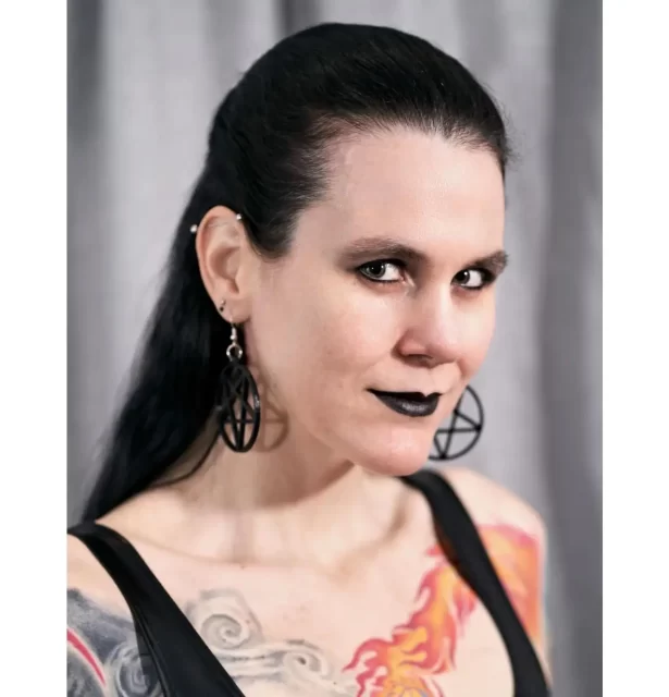 An image of Thista Minai. She is looking at the camera and is wearing black lipstick.